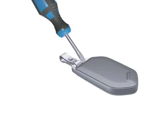 Kia K4 smart key fob disassembly step showing how to gently separate the outer back cover plastic housing using a precision plastic prying tool to access the inner battery compartment